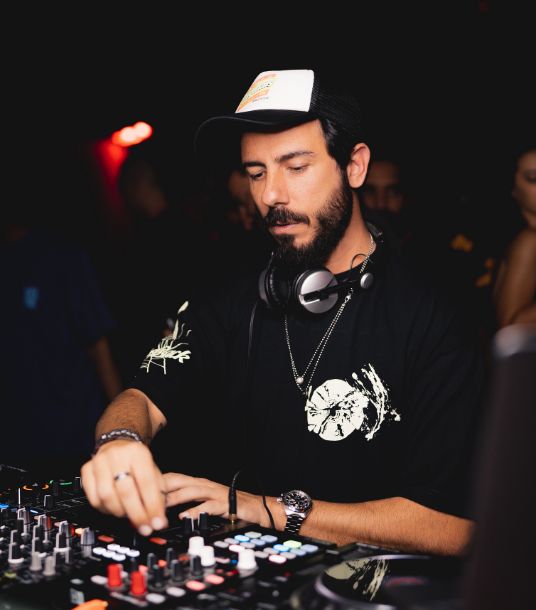 A DJ wearing a black t-shirt and cap.