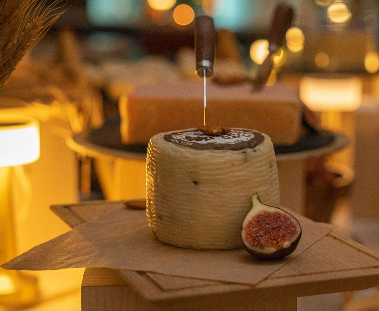 A block of cheese and a sliced fig on a table.