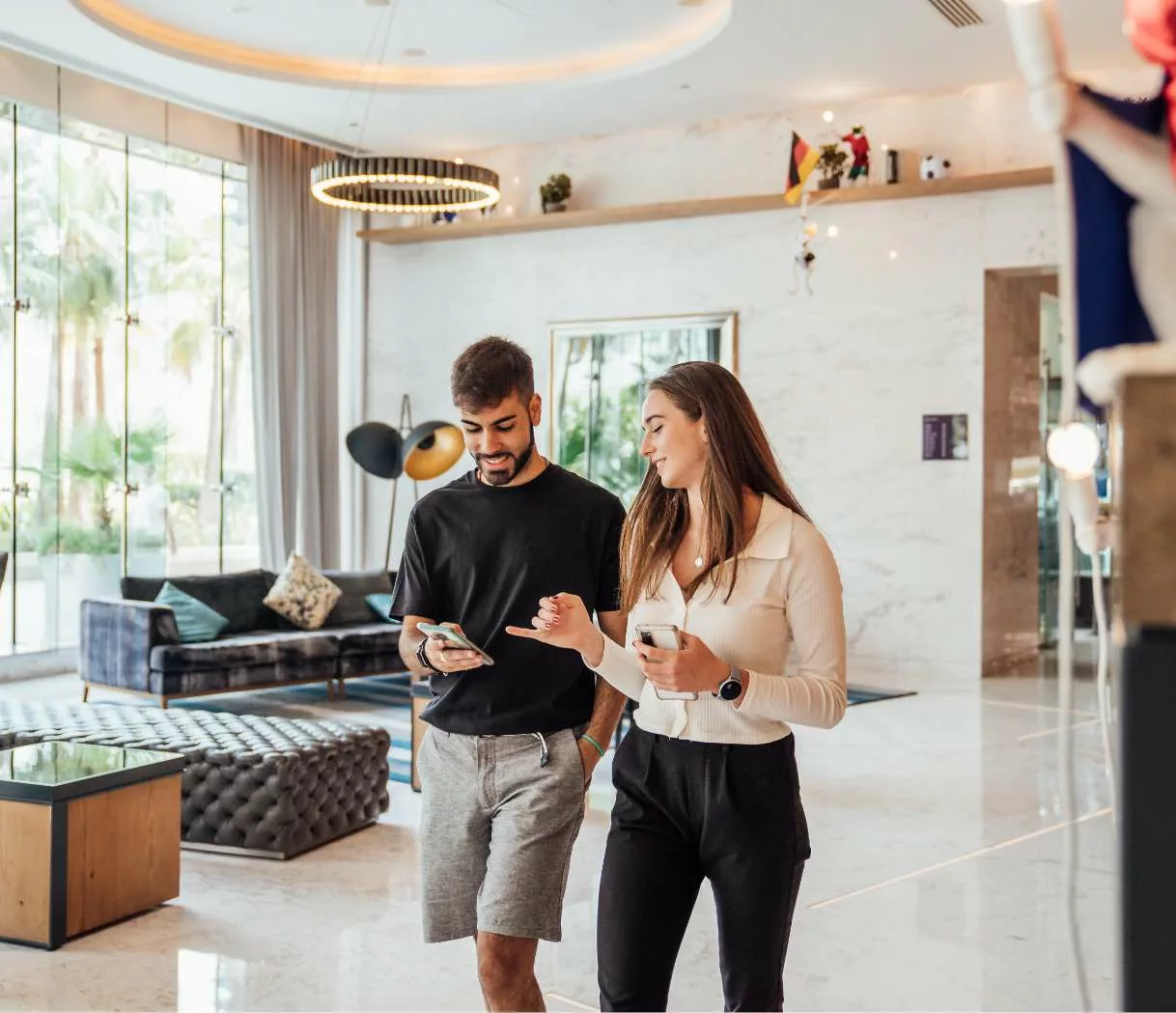 A couple walking through the hotel looking at a phone together.