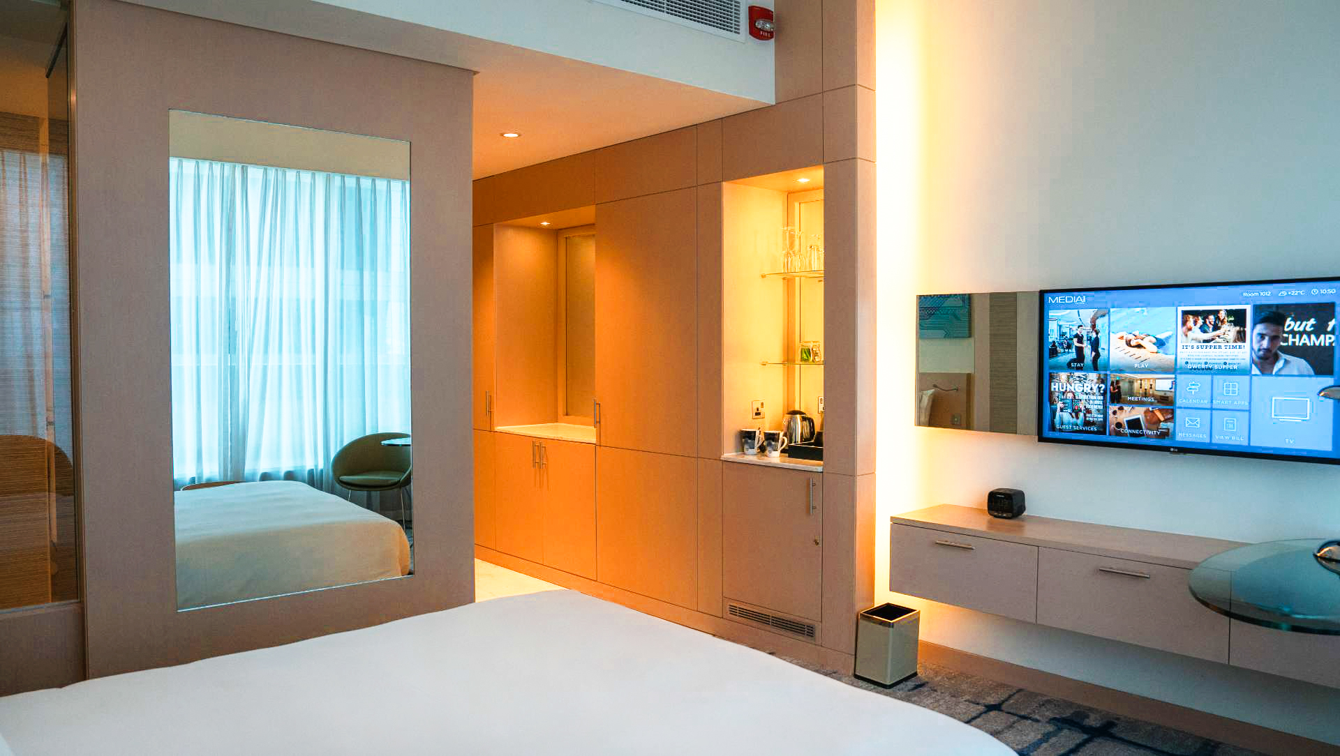 Media One Hotel room showing a tv, mirror and wardrobe space.